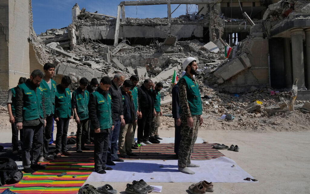 A cleric leads a group of volunteers in prayer next to a police facility struck during the US–Israeli military campaign in Tehran, Iran, March 4, 2026. (AP Photo/Vahid Salemi)
