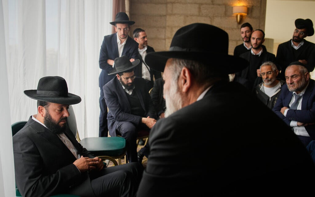 Friends and relatives comfort Yitzhak Biton, left, whose three children, Yaakov, Avigail and Sarah, were killed earlier this week when an Iranian missile struck their home in the city of Beit Shemesh, March 5, 2026. (AP Photo/Ohad Zwigenberg)