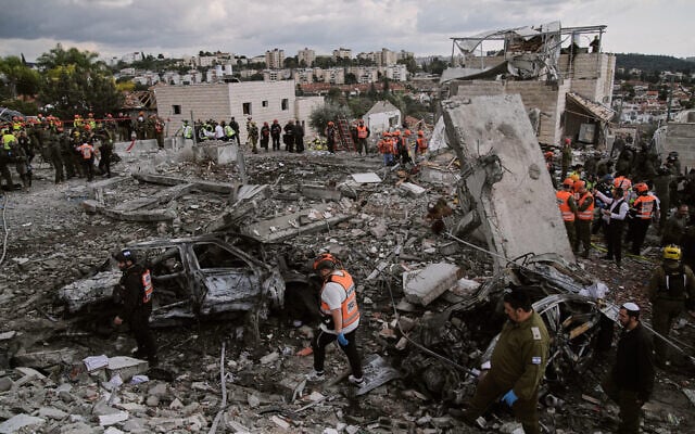 Rescue workers and military personnel operate at the scene where nine people were killed in an Iranian missile strike in Beit Shemesh, March 1, 2026. (AP Photo/ Leo Correa)