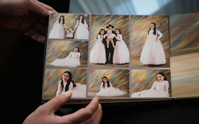 A relative shows photos of three siblings, Yaakov, Avigail and Sarah Biton, who were killed in a March 1 Iranian missile strike that hit their home in the city of Beit Shemesh, in Jerusalem on March 5, 2026. (AP/Ohad Zwigenberg)