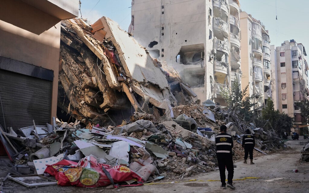 Hezbollah members walk past a building destroyed by an Israeli airstrike in Dahiyeh, Beirut's southern suburbs, Lebanon, Thursday, March 5, 2026. (AP Photo/Hassan Ammar)