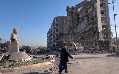 Residents pass in front of a destroyed building that housed a branch of Al-Qard Al-Hassan, a quasi-bank financial institution run by Hezbollah, which was hit by an Israeli airstrike in Dahiyeh, Beirut's southern suburbs, Lebanon, March 10, 2026. (AP Photo/Hussein Malla)