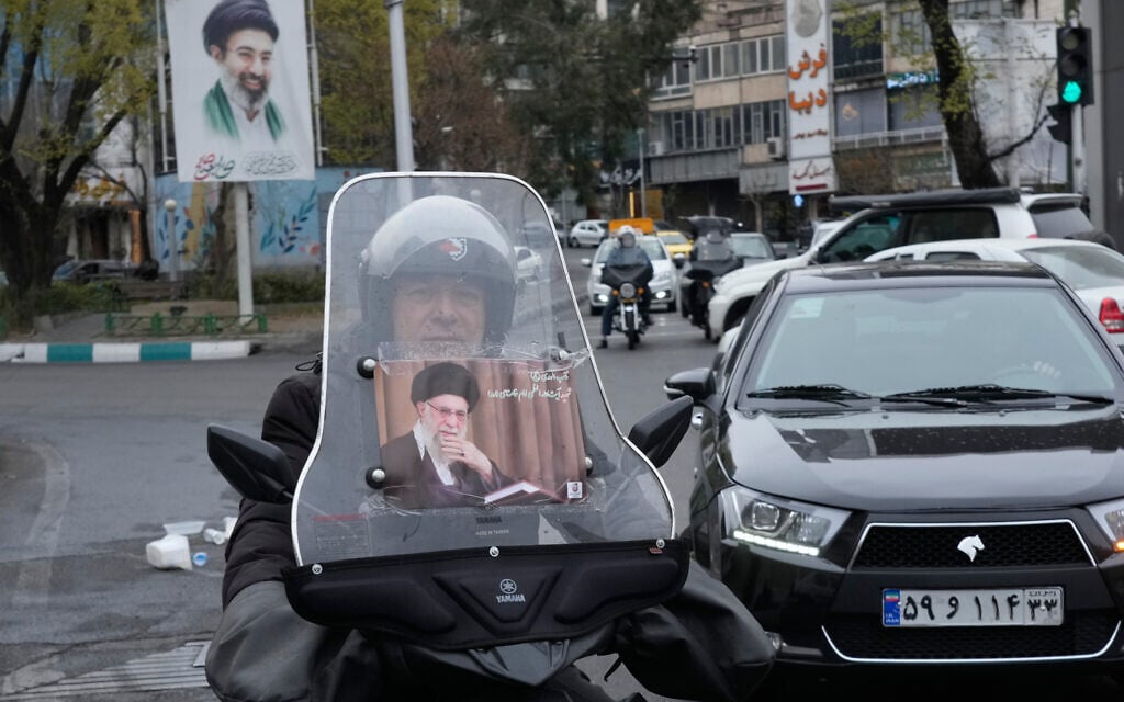 A man rides his motorcycle with a poster of slain Iranian supreme leader Ayatollah Ali Khamenei, as a banner at rear shows a portrait of his son and successor Ayatollah Mojtaba Khamenei, in downtown Tehran, Iran, March 10, 2026. (AP Photo/Vahid Salemi)