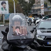 A man rides his motorcycle with a poster of slain Iranian supreme leader Ayatollah Ali Khamenei, as a banner at rear shows a portrait of his son and successor Ayatollah Mojtaba Khamenei, in downtown Tehran, Iran, March 10, 2026. (AP Photo/Vahid Salemi)