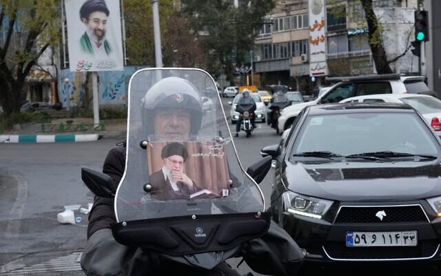 A man rides his motorcycle with a poster of slain Iranian supreme leader Ayatollah Ali Khamenei, as a banner at rear shows a portrait of his son and successor Ayatollah Mojtaba Khamenei, in downtown Tehran, Iran, March 10, 2026. (AP Photo/Vahid Salemi)