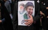 A mourner holds a poster depicting Ayatollah Mojtaba Khamenei, right, the successor to his late father Ayatollah Ali Khamenei, left, as supreme leader, during the funeral procession for senior Iranian military officials and civilians killed during the U.S.-Israel campaign in Tehran, Iran, March 11, 2026. (AP/Vahid Salemi)