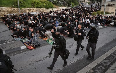 Israel Police officers pass by Palestinian Muslims as they perform Eid al-Fitr prayers outside Jerusalem's Old City, March 20, 2026. (AP Photo/Mahmoud Illean)