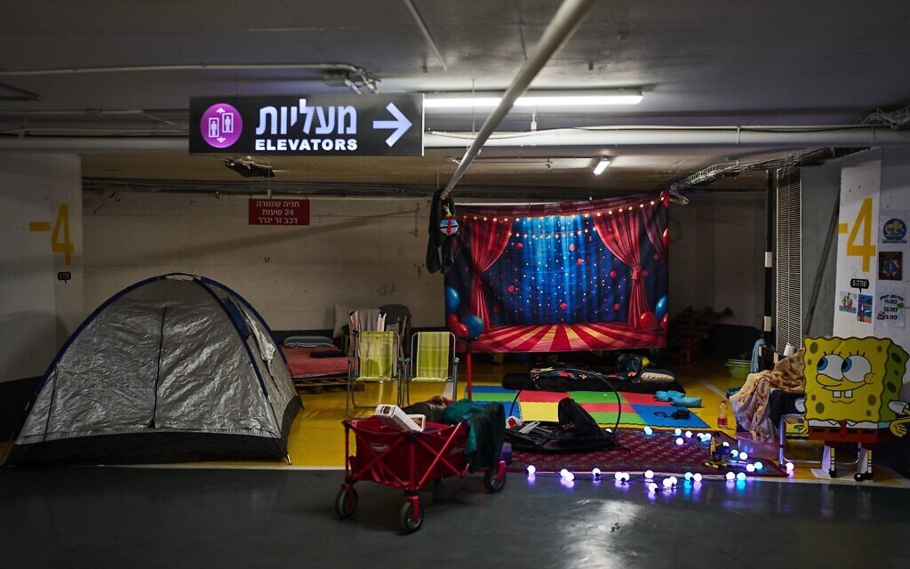 Tents, mattresses and children's toys are spread across an underground parking garage where people spend the night as a precaution against Iranian missile attacks in Tel Aviv, March 12, 2026. (AP Photo/Oded Balilty)