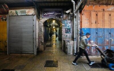 A man pushes a handcart past closed shops in Jerusalem's Old City, on March 27, 2026, as the area remains closed to visitors amid the war with Iran. (AP Photo/Mahmoud Illean)
