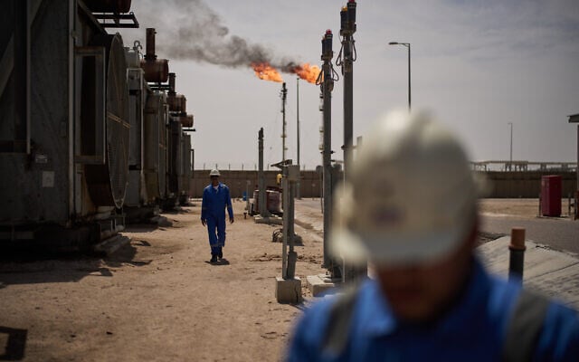 Workers walk in an area at a degassing station in Zubair oil field, whose operations have being reduced due to the Mideast war triggered by the US and Israeli attacks on Iran, near Basra, Iraq, March 28, 2026. (AP Photo/Leo Correa, File)