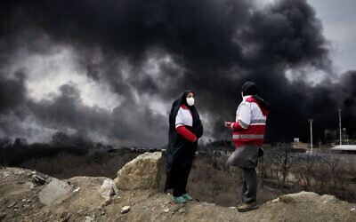 Two women from the Iranian Red Crescent Society stand as a thick plume of smoke from a US-Israeli strike on an oil storage facility late Saturday rises into the sky in Tehran, Iran on March 8, 2026. (AP Photo/Vahid Salemi) Two women from the Iranian Red Crescent Society stand as a thick plume of smoke from a US-Israeli strike on an oil storage facility late Saturday rises into the sky in Tehran, Iran on March 8, 2026. (AP Photo/Vahid Salemi)