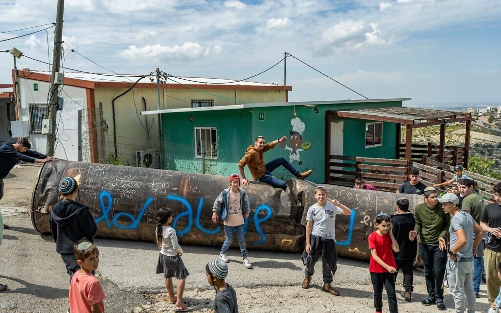 Children and teens surround debris from a ballistic missile fired from Iran that fell in the settlement of Pedu’el in the West Bank, on March 23, 2026 (Flash90)