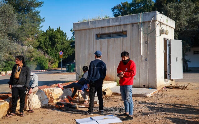 Thai workers stand near a reinforced shelter  in Moshav Yashresh as sirens sound following ballistic missiles fired from Iran toward Israel, March 2, 2026. (Yossi Aloni/Flash90)