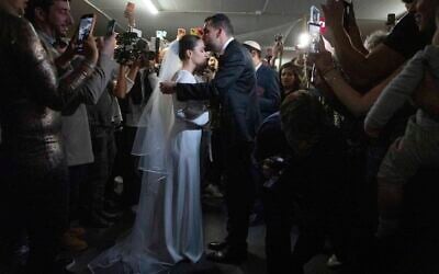 Lior and Misha stand during their wedding ceremony in an underground parking lot used as a bomb shelter in Tel Aviv, March 3, 2026. (Chaim Goldberg/Flash90)