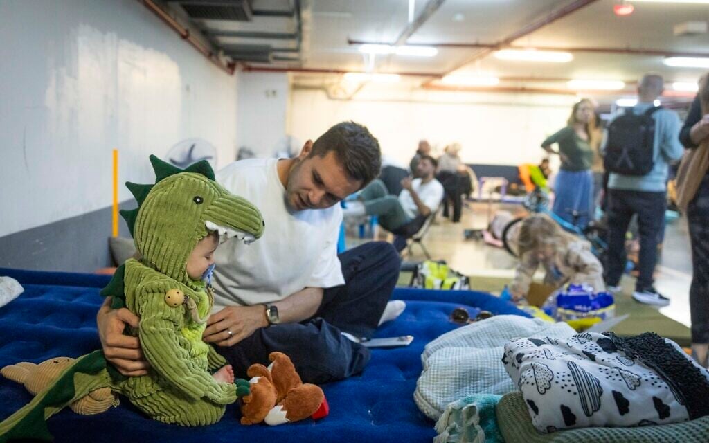 A child dressed up for the Jewish holidy of Purim takes cover from incoming Iranian missiles at an underground parking lot turned shelter in Tel Aviv, March 3, 2026. (Chaim Goldberg/Flash90)
