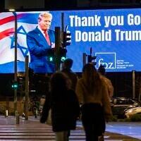 People walk past a sign reading “Thank you God & Donald Trump” in Tel Aviv, March 10, 2026. (Flash90)