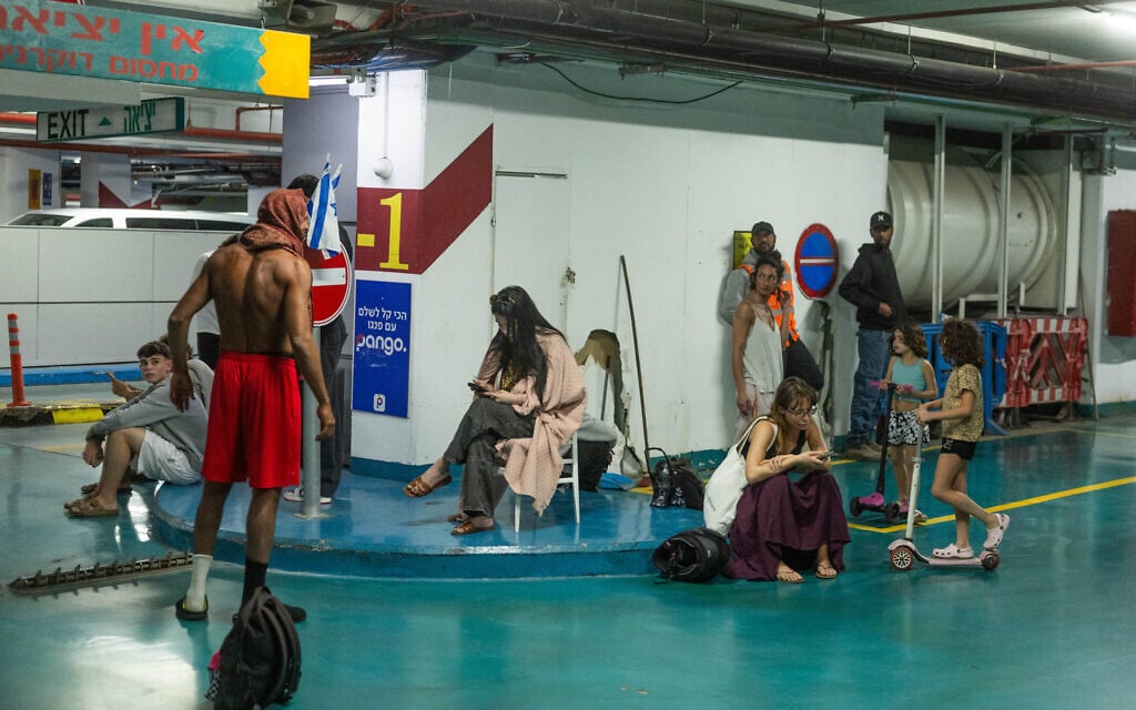 Israelis take shelter in an underground parking lot as a siren warns of incoming missilies fired from Iran into Israel, March 11, 2026. (Chaim Goldberg/Flash90)
