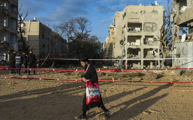 A man walks near where an overnight Iranian missile strike hit Arad, in southern Israel, on March 22, 2026. (Chaim Goldberg/ Flash90)
