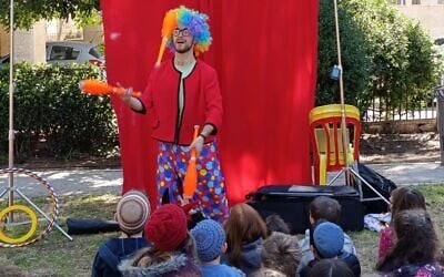 A clown performs at a park in Jerusalem's Katamon neighborhood, March 2, 2026 (Zev Stub/Times of Israel)