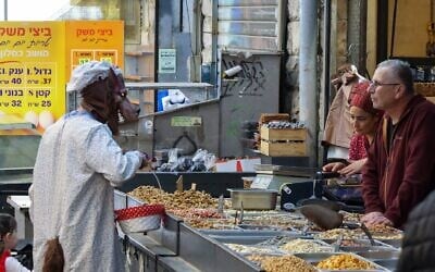 A man wearing a wolf costume with his daughter dressed as Little Red Riding Hood shops at a stall in the Mahane Yehuda market in Jerusalem, which was operating at limited capacity because of the war with Iran, during Purim in Jerusalem, March 4, 2026. (Theia Chatelle/ JTA)