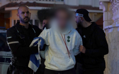 A young man suspected of spraypainting a Palestinian flag onto the Lod municipality building is arrested by police on March 11, 2026. (Israel Police)