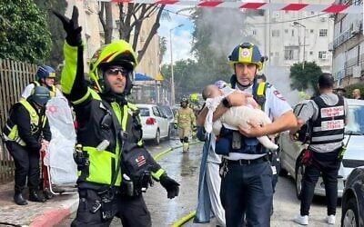 A rescue worker carries an infant from the scene of an Iranian missile strike in central Israel, March 31, 2026 (MDA)