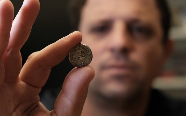 Ilan Hadad from the Israel Antiquities Authority holds a silver shekel coin seized during an inspection at the Hizma Checkpoint north of Jerusalem in the West Bank on February 20, 2026. (Yoli Schwartz/Israel Antiquities Authority)