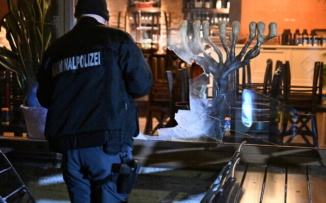 A detective stands with a flashlight in front of the smashed window of a Jewish-owned Israeli restaurant in Munich, Germany, on April 10, 2026. (Felix Hörhager/dpa via Reuters Connect) A detective stands with a flashlight in front of the smashed window of a Jewish-owned Israeli restaurant in Munich, Germany, on April 10, 2026. (Felix Hörhager/dpa via Reuters Connect)