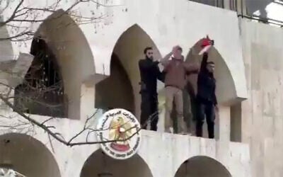 A man identified in Arabic media as a Syrian security officer, right, hoists a Palestinian flag he removed from the United Arab Emirates embassy building in Damascus, Syria, April 3, 2026, amid a pro-Palestinian, anti-Israel protest. (Screen capture: X, used in accordance with Clause 27a of the Copyright Law)