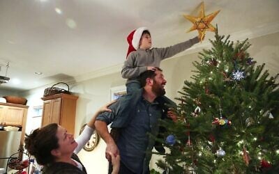 Illustrative: An interfaith family decorates the Christmas tree. (Pat Greenhouse/The Boston Globe via Getty Images/ via JTA)