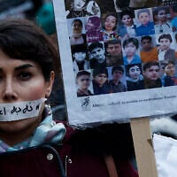 A demonstrator wears a sticker over her mouth with the words "no execution" next to the portraits of alleged victims of crackdowns, during a silent march denouncing the deadly crackdown on anti-government protesters in the Islamic Republic, in Paris on January 31, 2026. (Sébastien DUPUY / AFP)