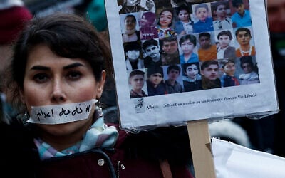 A demonstrator wears a sticker over her mouth with the words "no execution" next to the portraits of alleged victims of crackdowns, during a silent march denouncing the deadly crackdown on anti-government protesters in the Islamic Republic, in Paris on January 31, 2026. (Sébastien DUPUY / AFP)