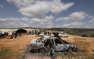 Palestinians stand near a vehicle that was destroyed following a settler attack on the outskirts of Al-Lubban ash-Sharqiya village, south of Nablus in the West Bank, on April 6, 2026. (JAAFAR ASHTIYEH / AFP)