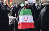 An Iranian woman wrapped in the national flag performs noon prayers as people gather in Tehran's Revolution Square after the United States and Iran agreed to a two-week ceasefire, on April 8, 2026. (ATTA KENARE / AFP) /