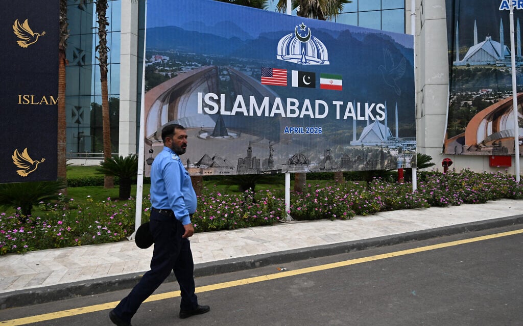 A police officer walks past a billboard for the US-Iran talks in Islamabad on April 11, 2026 (Aamir QURESHI / AFP)