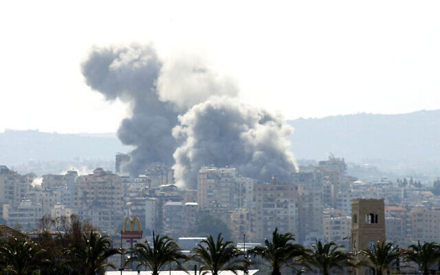 Smoke rises behind palm trees and a McDonald's 'Golden Arches' logo from the site of an Israeli airstrike that targeted the Al-Hosh area near the coastal Lebanese city of Tyre on April 14, 2026. (Kawnat HAJU / AFP)