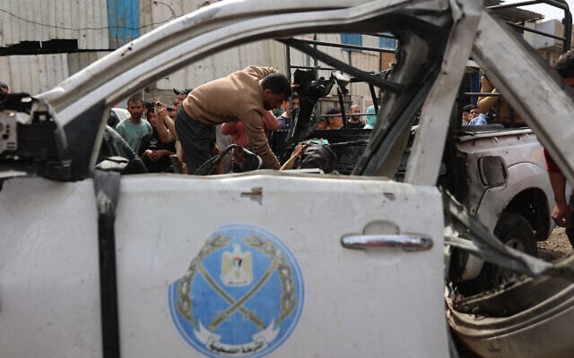 A Palestinian inspects the remains of a police vehicle destroyed in a reported Israeli strike that killed several people, in Gaza City on April 14, 2026. (Omar AL-QATTAA / AFP)