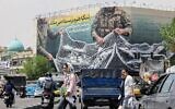 Iranian walks past a giant billboard reading "the Strait of Hormuz remains closed," at Revolution Square in Tehran on April 22, 2026. (Atta Kenare/AFP)