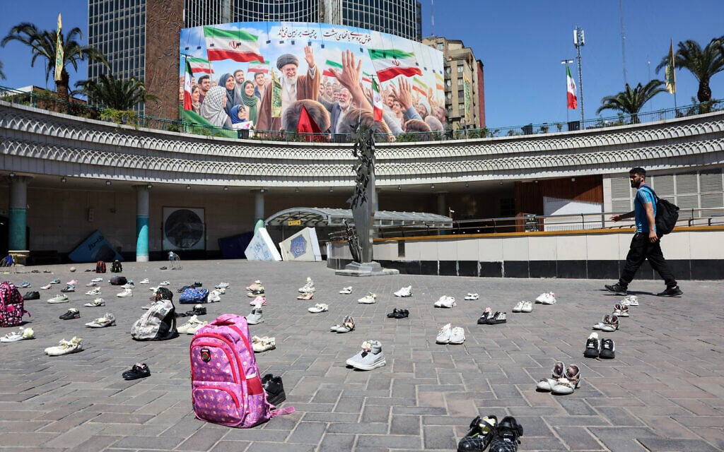 An Iranian man walks past symbolic belongings laid on the ground at Valiasr Square in Tehran on April 24, 2026, in tribute to the schoolgirls in Minab killed in an airstrike. A large billboard depicting Iran's slain supreme leader Ali Khamenei is visible in the background. (AFP) An Iranian man walks past symbolic belongings laid on the ground at Valiasr Square in Tehran on April 24, 2026, in tribute to the schoolgirls in Minab killed in an airstrike. A large billboard depicting Iran's slain supreme leader Ali Khamenei is visible in the background. (AFP)