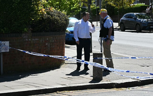 A person talks to a security officer at a cordon following a stabbing attack in the Golders Green neighborhood of north London, on April 29, 2026. (JUSTIN TALLIS / AFP)