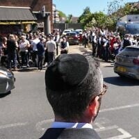 A local resident looks out as crowds gather during a visit by Britain's Prime Minister Keir Starmer to an ambulance center operated by the Jewish community in the Golders Green neighborhood of north London on April 30, 2026, the day after two men were stabbed in an attack. (CARLOS JASSO / AFP)
