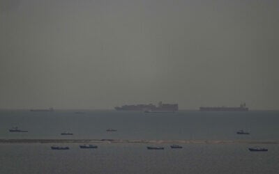 Fishing boats dot the sea as cargo ships, in the background, sail through the Arabian Gulf toward the Strait of Hormuz off the United Arab Emirates, March 27, 2026. (AP Photo)