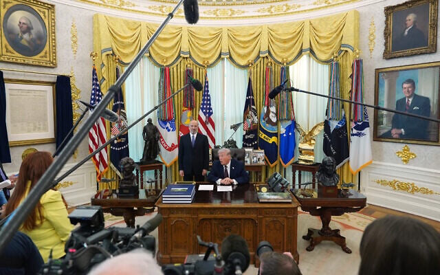 US President Donald Trump answers questions from reporters after signing an executive order in the Oval Office of the White House, March 31, 2026, in Washington, as Commerce Secretary Howard Lutnick listens. (AP Photo/Alex Brandon)