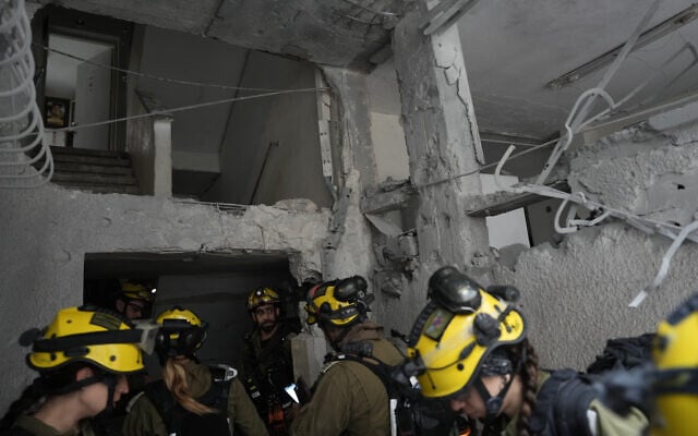 Rescue teams inspect an impact site following an Iranian ballistic missile strike, in Bnei Brak, April 1, 2026. (AP Photo/Oded Balilty)