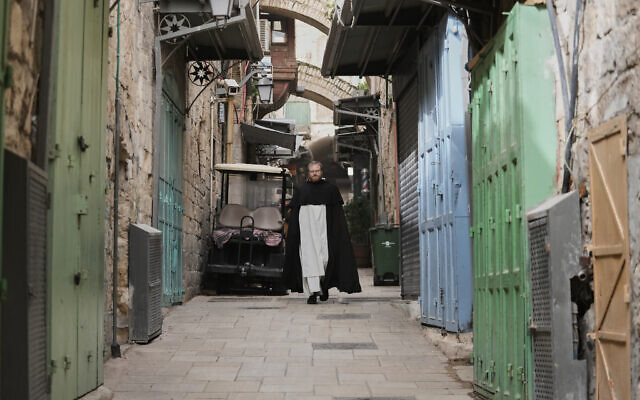 A Catholic clergyman walks through an alley of Jerusalem's Old City, largely empty due to restrictions linked to the Iran war, on Good Friday, April 3, 2026. (AP Photo/Mahmoud Illean)