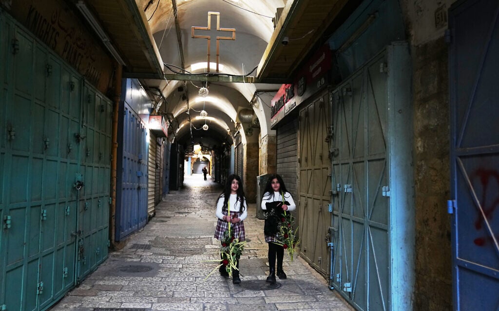 Orthodox Christians walk holding palm branches in Jerusalem's Old City for Palm Sunday, largely empty due to restrictions linked to the Iran war, Sunday, April 5, 2026. (AP/Mahmoud Illean)