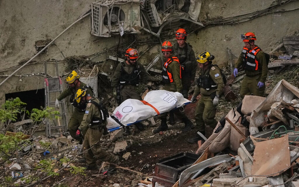 Rescue workers and military personnel carry a body of a victim from the rubble of a residential building a day after it was struck by an Iranian missile in Haifa, Israel, April 6, 2026. (AP Photo/Ariel Schalit)