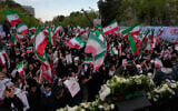 People wave Iranian flags and chant slogans in a memorial for school children who were killed during a strike on a school in southern town of Minab on February 28, in downtown Tehran, Iran, April 7, 2026. (AP Photo/Vahid Salemi)