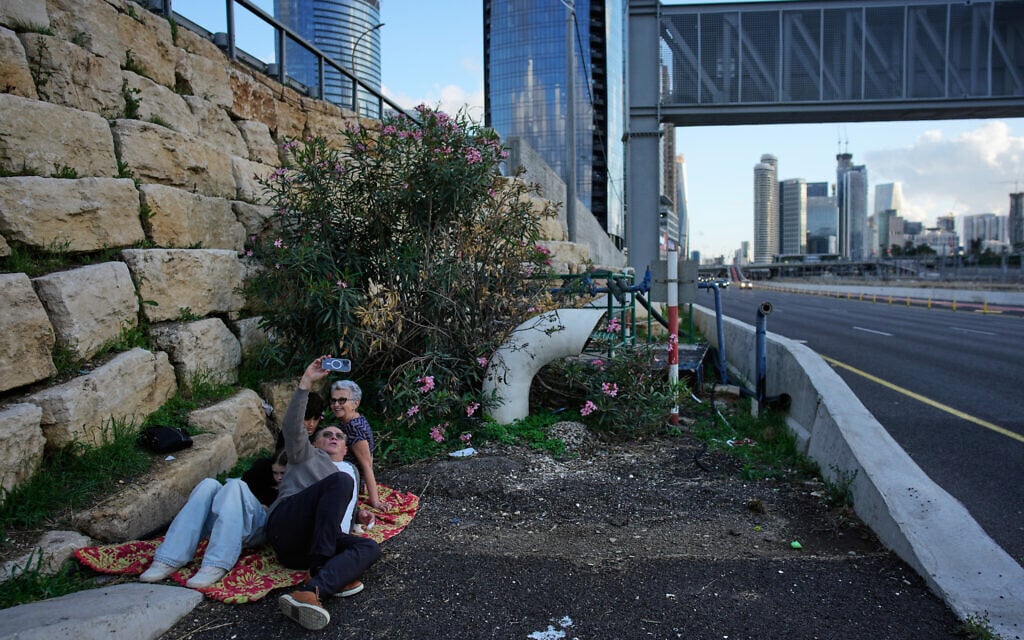 People take take a selfie along a highway as air raid sirens warn of an incoming Iranian missile strike in Tel Aviv, Israel, April 7, 2026. (AP Photo/Ohad Zwigenberg)