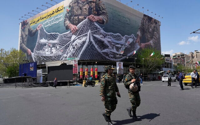 Two police officers walk in front of an anti-US billboard depicting American aircraft being caught by Iranian armed forces in a fishing net beneath the words in Farsi, "The Strait of Hormuz will remain closed, The entire Persian Gulf is our hunting ground," in Tehran, Iran, Sunday, April 5, 2026. (AP/Vahid Salemi)